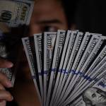 Seorang pembeli menunjukkan uang Dolar Amerika Serikat yang ditukarnya di gerai penukaran valuta asing, Jakarta, Senin (15/7/2019).