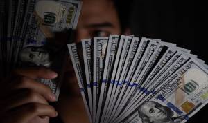Seorang pembeli menunjukkan uang Dolar Amerika Serikat yang ditukarnya di gerai penukaran valuta asing, Jakarta, Senin (15/7/2019).